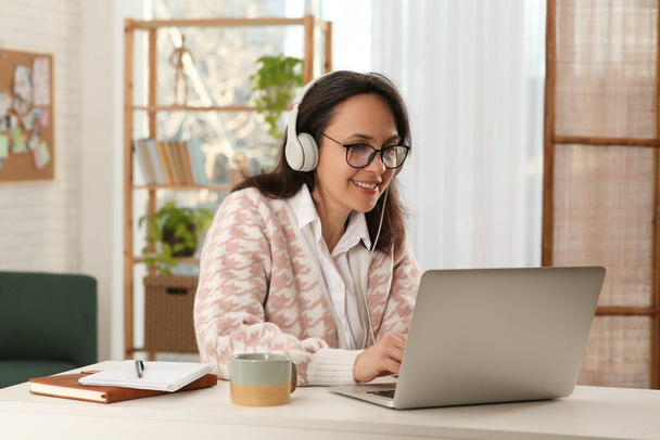 Woman with modern laptop and headphones learning at home - Foto, Imagen
