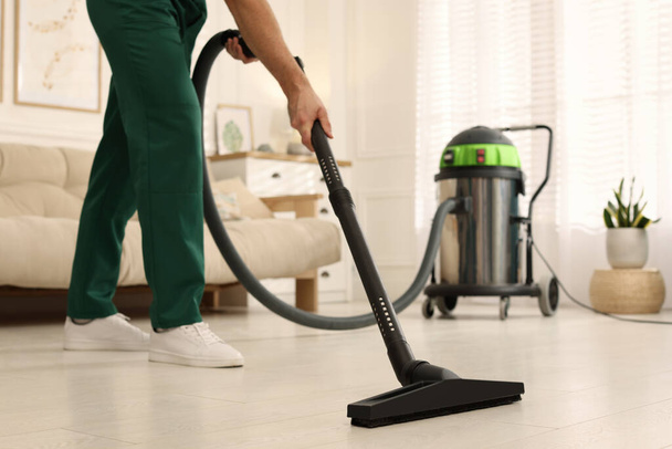 Professional janitor vacuuming floor in living room, closeup - Valokuva, kuva