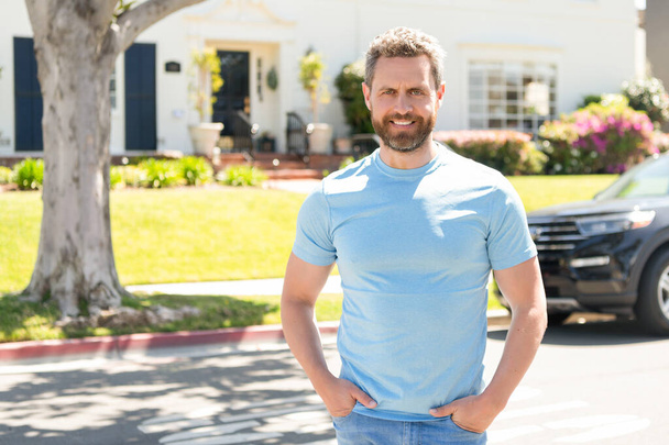 cheerful guy standing next to car and house in neighborhood - Foto, imagen
