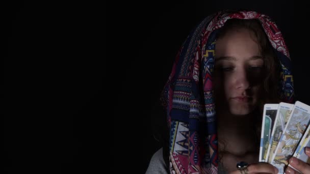 Giovane ragazza con una sciarpa che mostra i tarocchi - Filmati, video