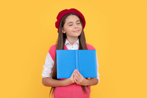 marzycielski nastolatek szkoła dziewczyna w francuski beret czytania książki na żółtym tle, wyobraźnia - Zdjęcie, obraz