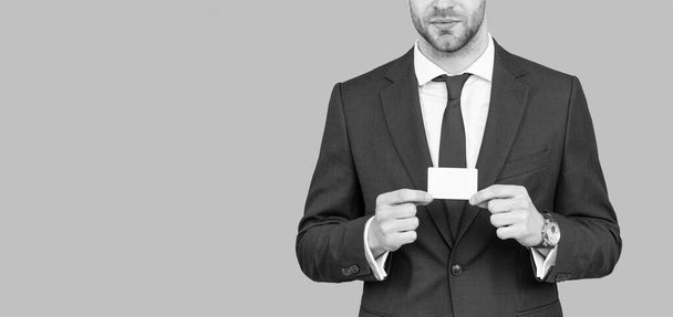 bijgesneden zakenman houden credit card met kopieerruimte op grijze achtergrond, bankieren - Foto, afbeelding
