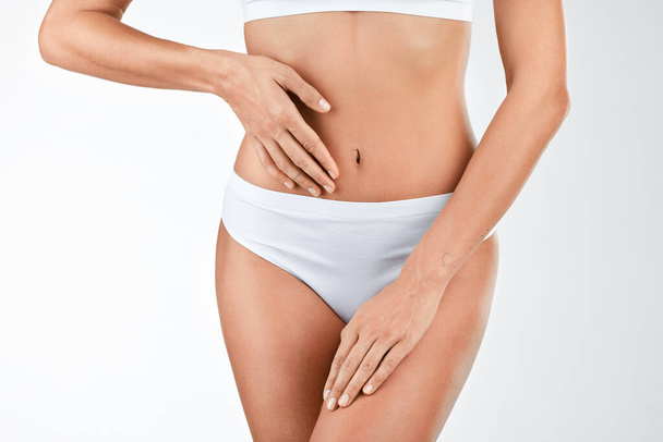 Mantener un microbioma intestinal saludable. Fotografía de una mujer tocando su estómago contra un fondo de estudio. - Foto, imagen