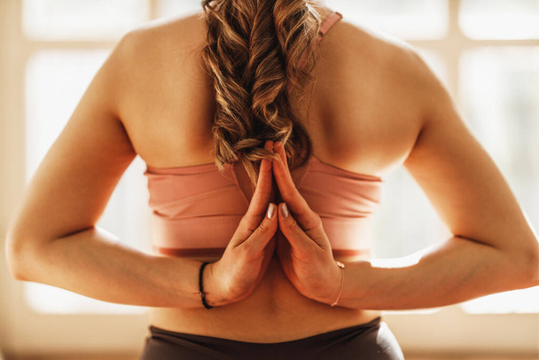 Крупный план расслабленной молодой женщины, практикующей йогу в позе "Back Namaste" дома. - Фото, изображение