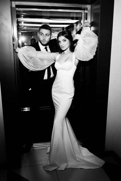 black and white photo of bride and groom posing in the lift - Fotografie, Obrázek