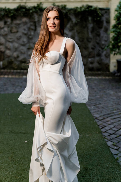 beautiful young woman in a white dress posing outdoors - Foto, afbeelding