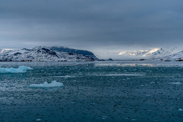 Θάλασσα με παγάκια που λιώνουν, χιονισμένα βουνά στο Σβάλμπαρντ της Νορβηγίας. Υπερθέρμανση του πλανήτη. - Φωτογραφία, εικόνα
