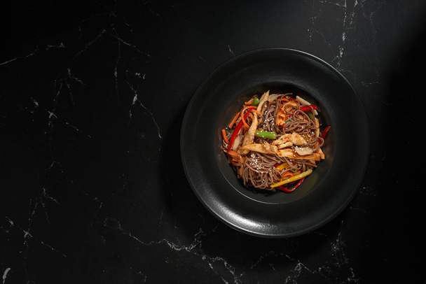Top view, Soba beef and vegetables, Buckwheat noodles on a dark stone background. Asian cuisine, Wok menu. Traditional Asian food - Foto, Imagem