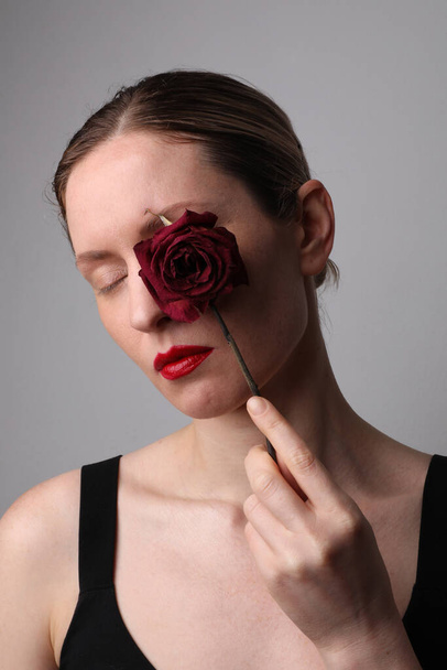 Young woman with dry rose. Skin anti-aging treatment. Vertical. - Fotó, kép