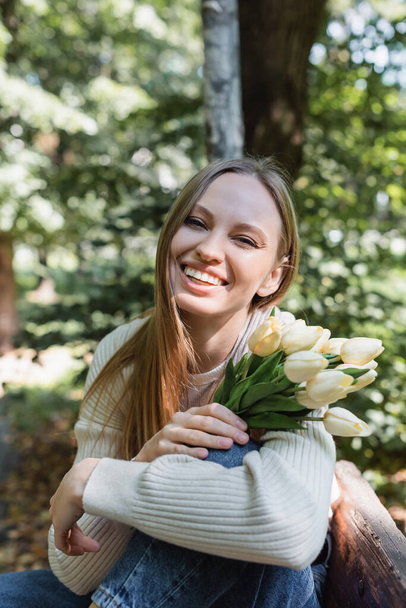 happy woman holding blooming tulips in green park - 写真・画像