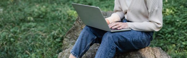 cropped view of woman using laptop while sitting on stone, banner - Photo, image