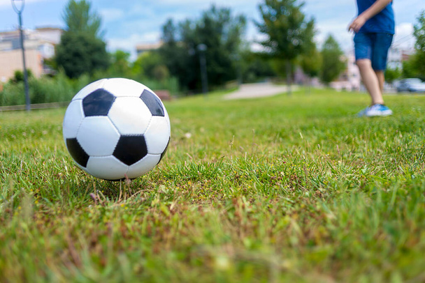 Low angle view of ball on park grass kicked by a child - Φωτογραφία, εικόνα
