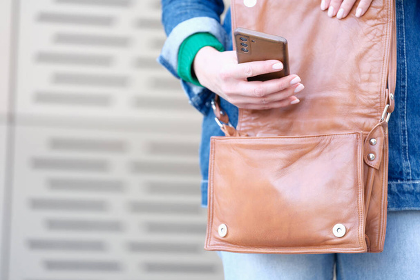 Woman hand opens a bag and holds smartphone - Foto, Bild