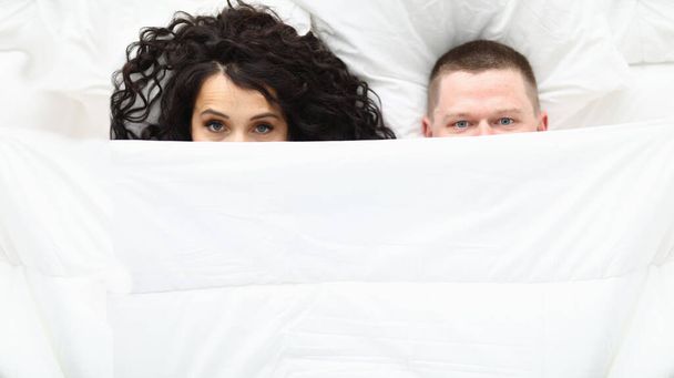 Мужчина и женщина, покрытые белым одеялом, проснувшаяся пара в плохом состоянии - Фото, изображение
