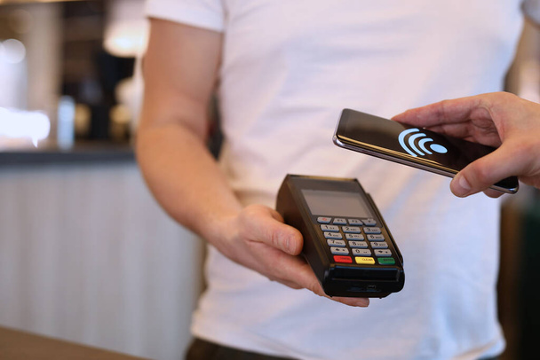 Férfi fizet mobiltelefonnal keresztül pos terminál NFC technológiával - Fotó, kép