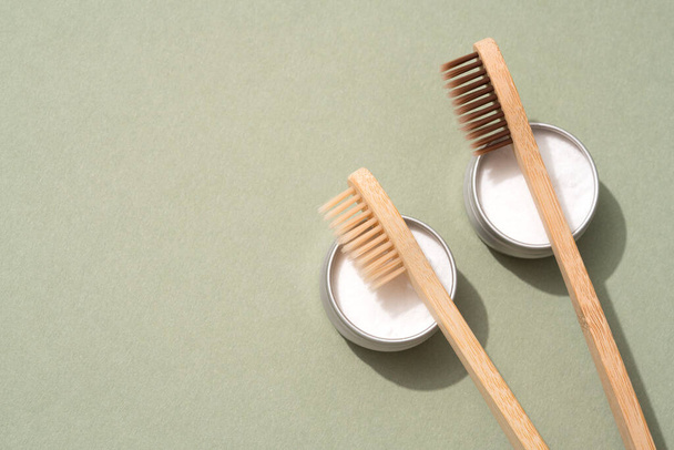 Set of bamboo toothbrushes and mineral toothpowder on green background with copy space. Natural bath products, organic dentifrice. Mockup image, top view - 写真・画像