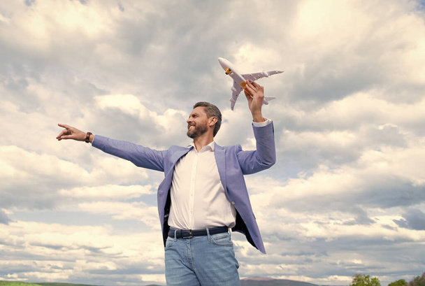 χαρισματικός χαρούμενος επιχειρηματίας με σακάκι κρατήσει αεροπλάνο παιχνίδι στον ουρανό φόντο, ιδέα - Φωτογραφία, εικόνα