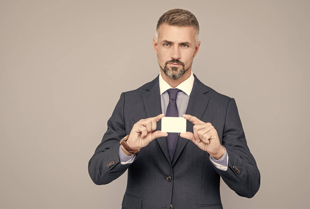 ώριμος τραπεζίτης με τριμμένα μαλλιά στο κοστούμι που δείχνει χώρο αντιγραφής πιστωτικής ή χρεωστικής κάρτας, διαχειριστής - Φωτογραφία, εικόνα
