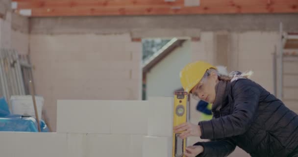 Γυναίκα μηχανικός που εξετάζει τσιμεντένιο τοίχο με επίπεδο - Πλάνα, βίντεο