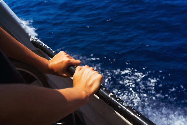 Eller, güvertenin korkuluklarında denizin arka planına karşı. Feribotla deniz yolculuğu. - Fotoğraf, Görsel