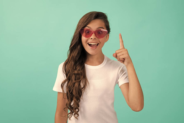 happy kid long curly hair in sunglasses casual style inspired with idea on blue background, idea - Foto, afbeelding
