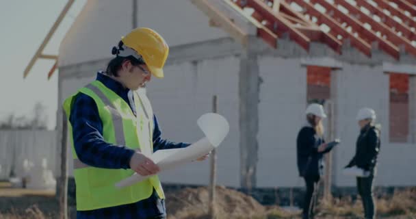 Confident young male construction worker analyzing blueprint - Materiaali, video