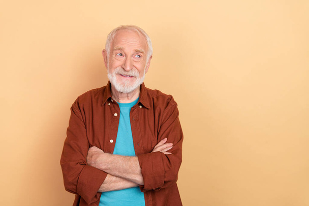 Fénykép a kíváncsi öreg fehér frizura férfi keresztbe karok néz hirdetés kopás barna ruhát elszigetelt bézs színű háttér - Fotó, kép