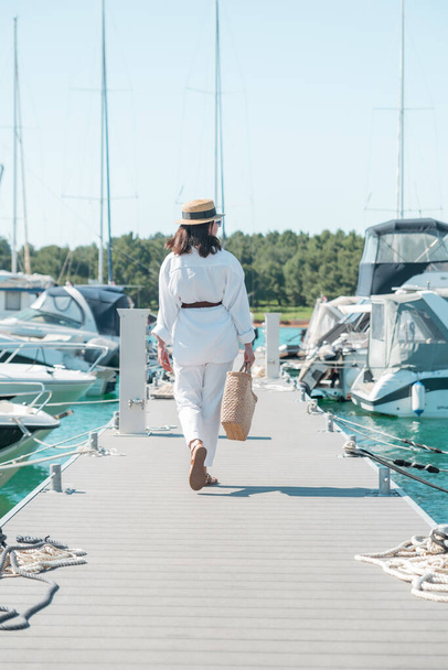молодая красивая женщина в белой летней одежде прогуливается по пристани для яхт. копировальное пространство - Фото, изображение