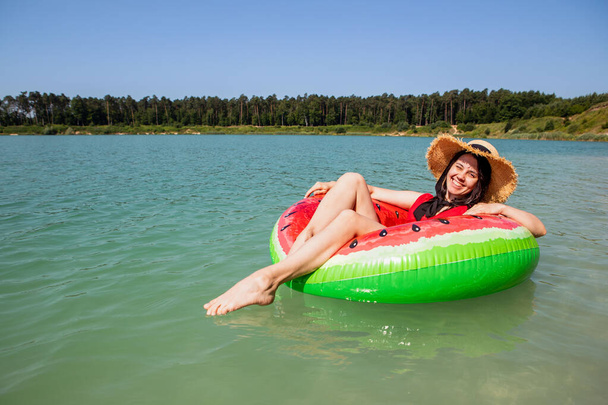 красивая женщина плавает на надувном кольце в голубом озере воды летний солнечный день - Фото, изображение