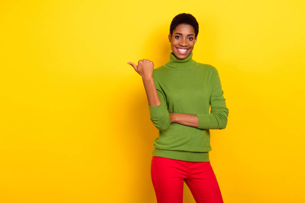 Photo of shiny cute trans woman wear green turtleneck pointing thumb empty space isolated yellow color background - Valokuva, kuva
