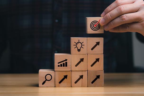 Success Concepts and Business Goals. Hand placed wooden block or selected on the table with action plan icon. Company strategy development - Fotó, kép