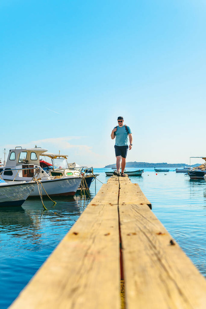Mann steht auf Holzsteg an Bootsanlegestelle in Seebucht. Sommerzeit - Foto, Bild