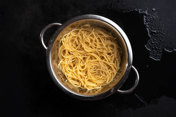 дуршлаг с приготовленными спагетти на темном фоне - Фото, изображение