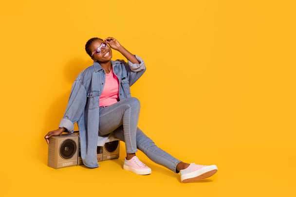 Full length portrait of satisfied glad person sitting boom box hand touch glasses isolated on yellow color background - Foto, Bild