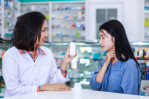 lekarz kobieta wyjaśnia wydaje medykację i daje porady dla młodych azjatyckich kobiet pacjentów z bólem gardła w aptece Tajlandia  - Zdjęcie, obraz