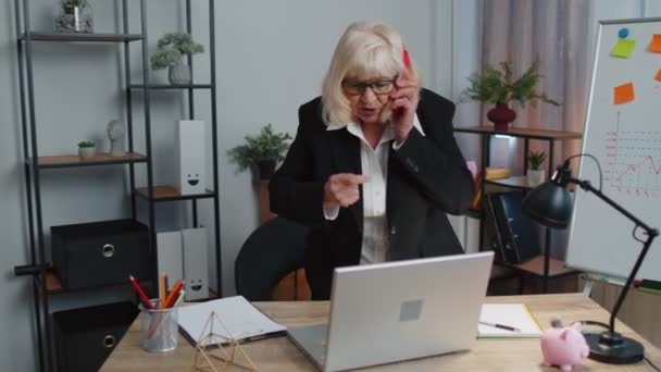 Wütende Senior-Geschäftsfrau telefoniert bei Büroarbeit genervt Chef redet Handy-Streit - Filmmaterial, Video