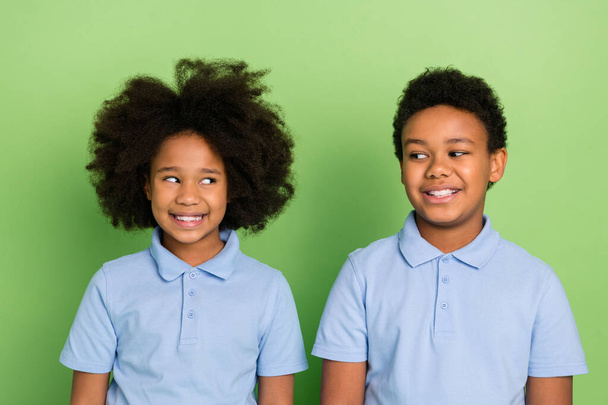 Portrait of two attractive cheerful trendy pre-teen kids looking at each other isolated over green color background - Foto, Imagen