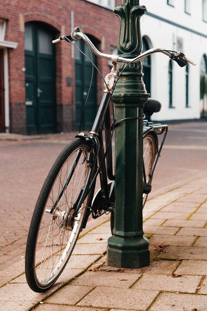 Vintage bike parked and locked on a street light post in the Netherlands. - Foto, Imagem