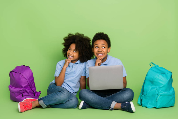 Portrait of attractive cheery pre-teen trendy friends friendship using laptop doing homework think isolated on green color background - Фото, изображение