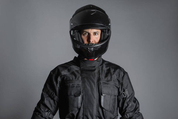 Студія знімає мотоцикліста в чорному обладнанні, дивлячись на камеру.. - Фото, зображення