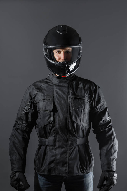 Studio shot of Motorcyclist biker in black equipment looking at camera. - Foto, Bild