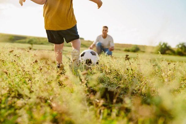 Young white father and his little son playing football together outdoors - Foto, Bild