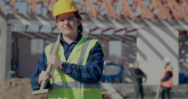 Itsevarma miespuolinen työntekijä kantaa lapiota olkapäällä - Materiaali, video