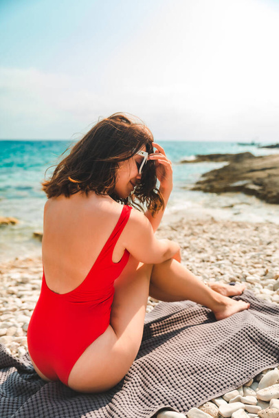 vrouw zitten op deken aan zee strand zomer vakantie concept - Foto, afbeelding