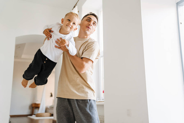 Νεαρός λευκός πατέρας κάνει πλάκα και παίζει με το γιο του στο σπίτι - Φωτογραφία, εικόνα