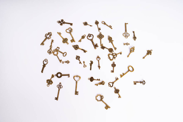 A pile of vintage golden skeleton keys isolated on white background. Golden skeleton keys in different shapes. Keys for locks and treasure boxes with unique shapes and designs. - Photo, image