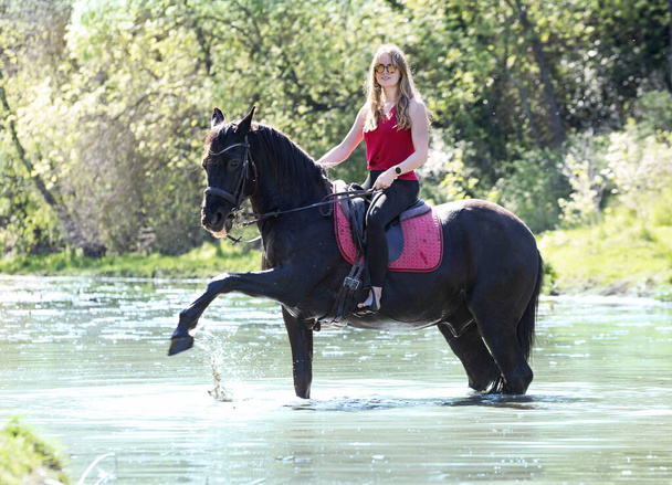  riding girl are training her black horse in a river - 写真・画像