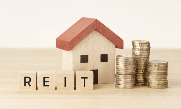 REIT Ingatlanbefektetési bizalom koncepció. Ház modell, pénz és fa blokkok szöveges - Fotó, kép