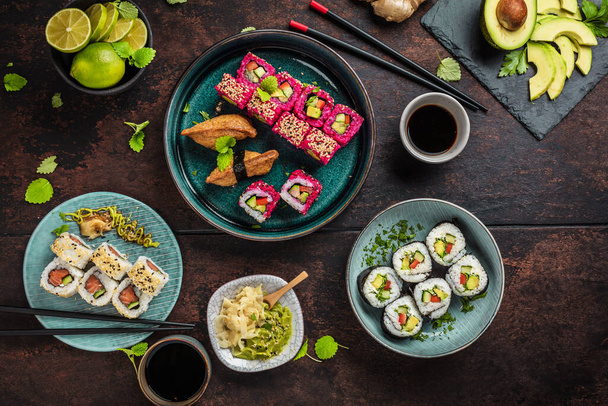 japanese sushi food. Maki ands rolls with tuna, salmon, shrimps, crab and avocado. Top view of assorted sushi. Rainbow sushi rolls, uramaki, hosomaki and nigiri. - Foto, Bild