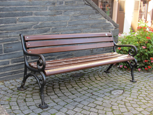 Деревянная скамейка с железными перилами на каменном тротуаре
 - Фото, изображение